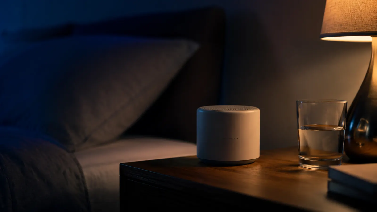White noise machine on a nightstand in a softly lit adult bedroom at night