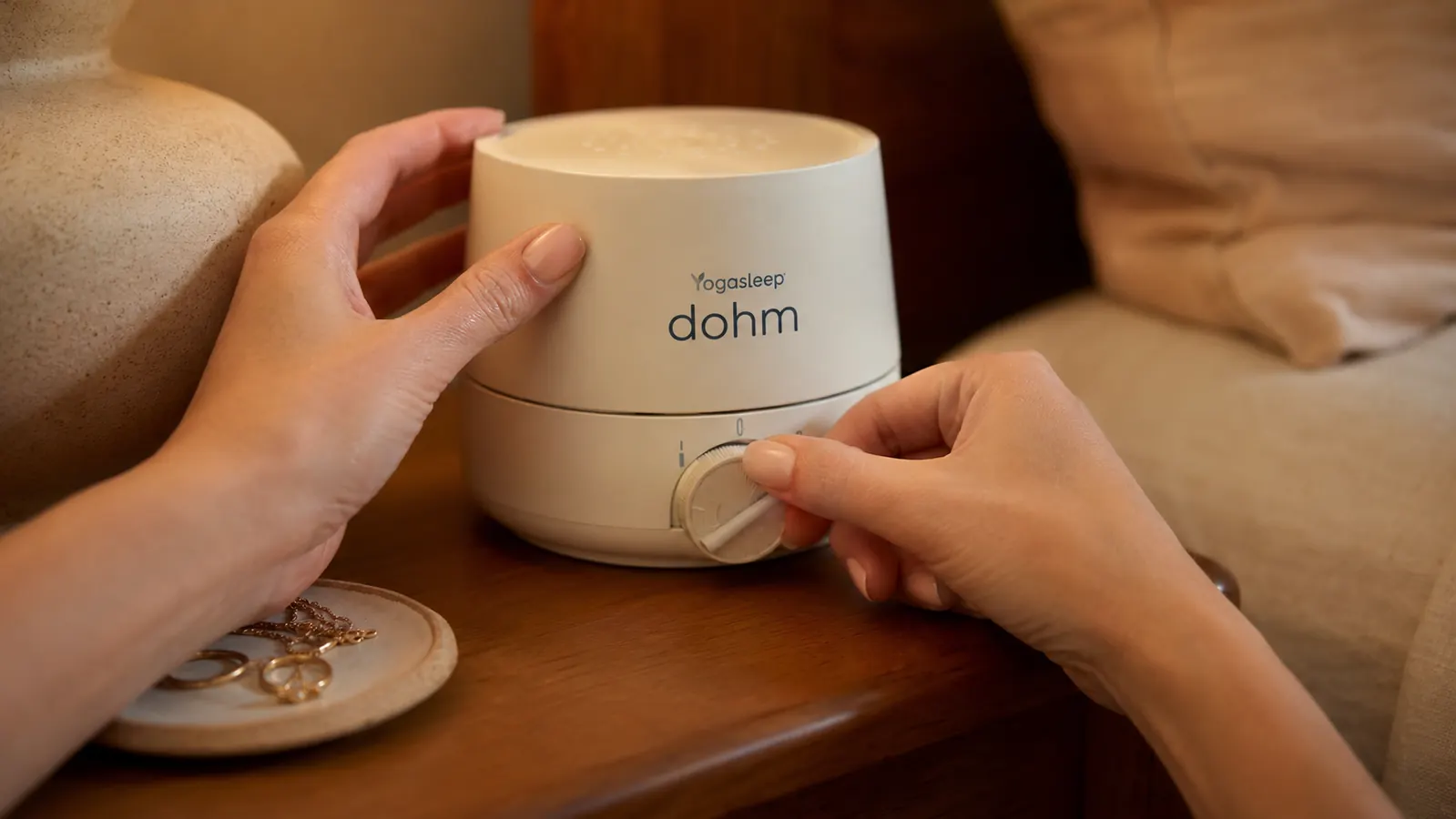 Hand adjusting the tone dial on the Yogasleep Dohm Classic white noise machine